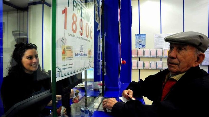 Un hombre observa el cartel del premio ante la atenta mirada de Rebeca Soto. // I.Abella