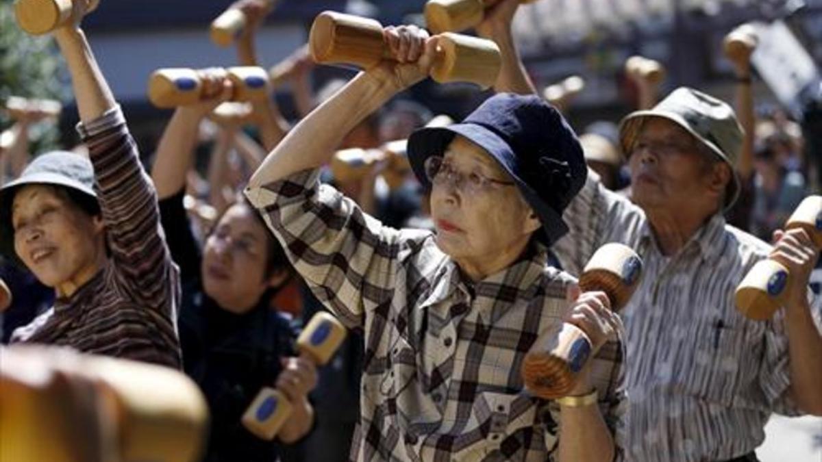 Activos 8Unos ancianos japoneses realizan ejercicio con unas mancuernas de madera en Tokio.
