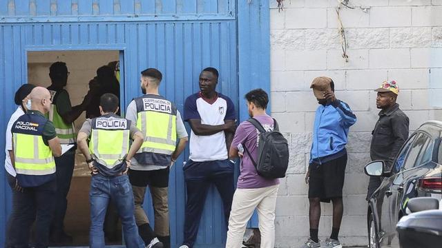 Agents de Policia i migrants a la porta d’una nau d’El Tarajal habilitada per fer filiacions, ahir. | REDUAN / EFE