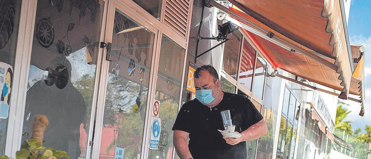 Un trabajador de una terraza limpia una de las mesas del establecimiento.