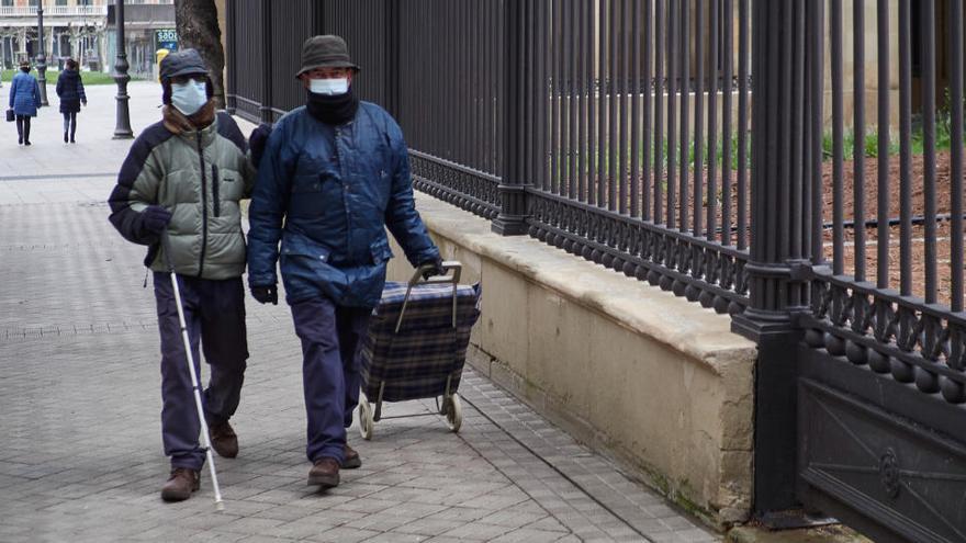 Dues persones caminen pel carrer amb mascareta, a Pamplona