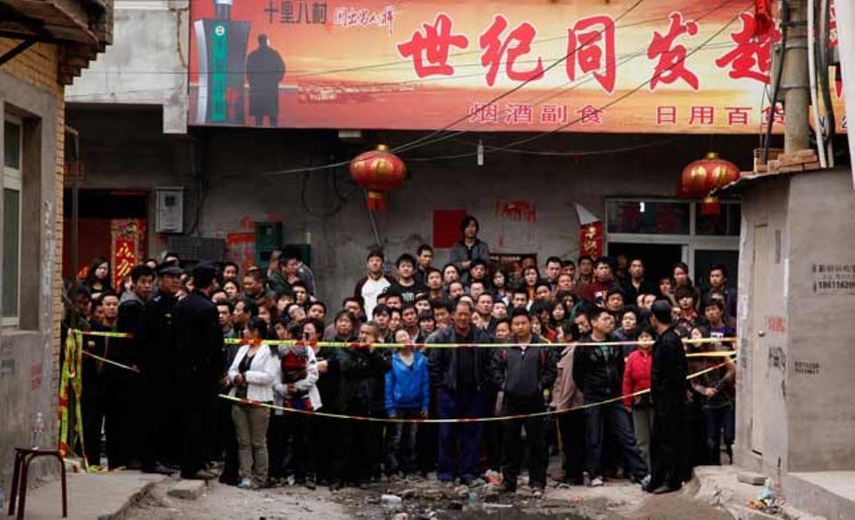 Un grup de veïns espera en un carrer tallat al districte de Dixing, a Pequín (Xina), on un incendi ha causat set morts dilluns al matí.