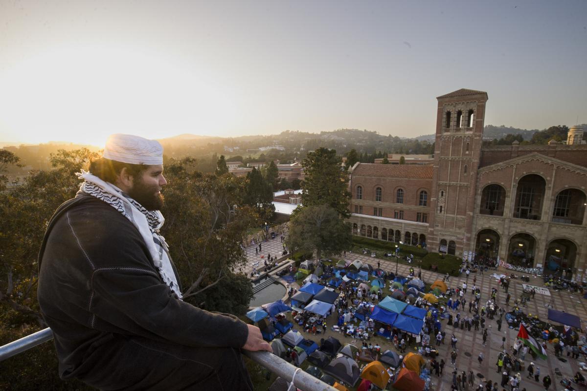 A demonstrator watches an encampment from a construction scaffold on the UCLA campus, after clashes between Pro-Israel and Pro-Palestinian groups the previous night, Wednesday, May 1, 2024, in Los Angeles. (AP Photo/Ethan Swope)