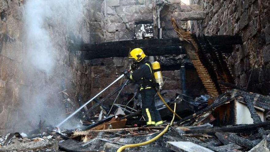 Un bombero trabajando ayer en el inmueble siniestrado el lunes. // Rafa Vázquez