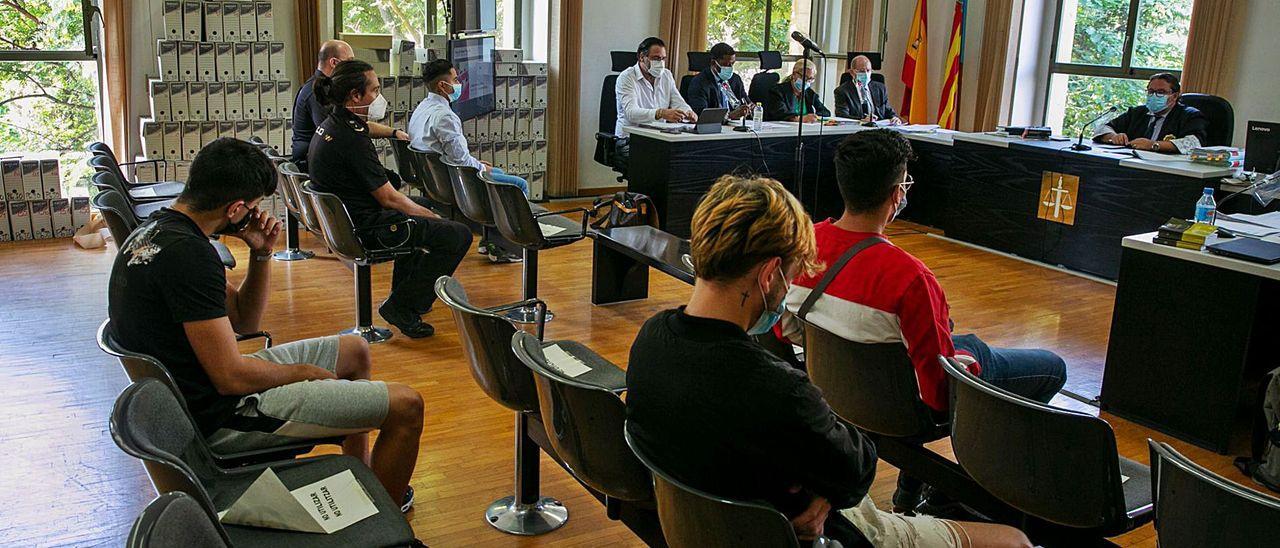 Los cuatro acusados mayores de edad de la agresión en el Monte Tossal, uno de ellos con custodia policial, en la sala de vistas. / RAFA ARJONES