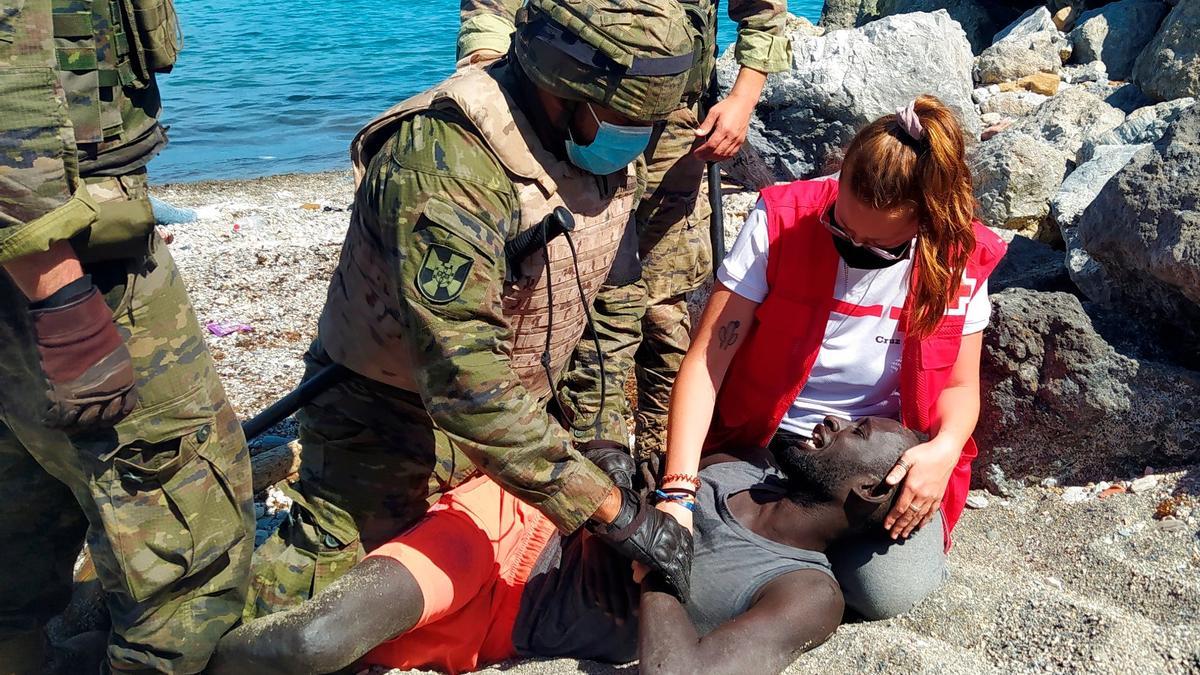 Militar y equipo de Cruz Roja ayudan a un inmigrante.