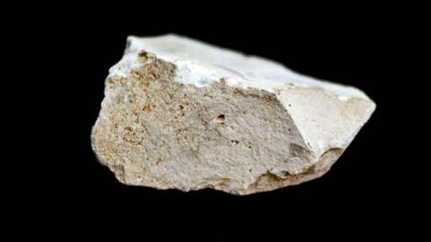 Detalle del pequeño cuchillo de sílex tallado hace 1,4 millones de años. A la derecha, un cráneo encontrado en la Cueva del Mirador.