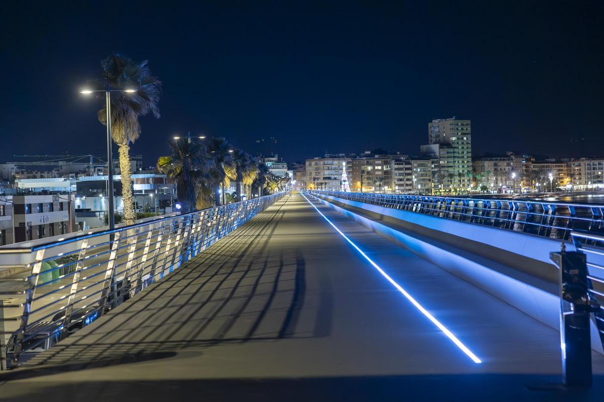 Aspecto nocturno de una de las zonas de pérgola con mirador, en la que se han instalado más bancos. La iluminación led se mantiene a lo largo de los 1.300 metros linieales. El casco urbano de Torrevieja, al fondo