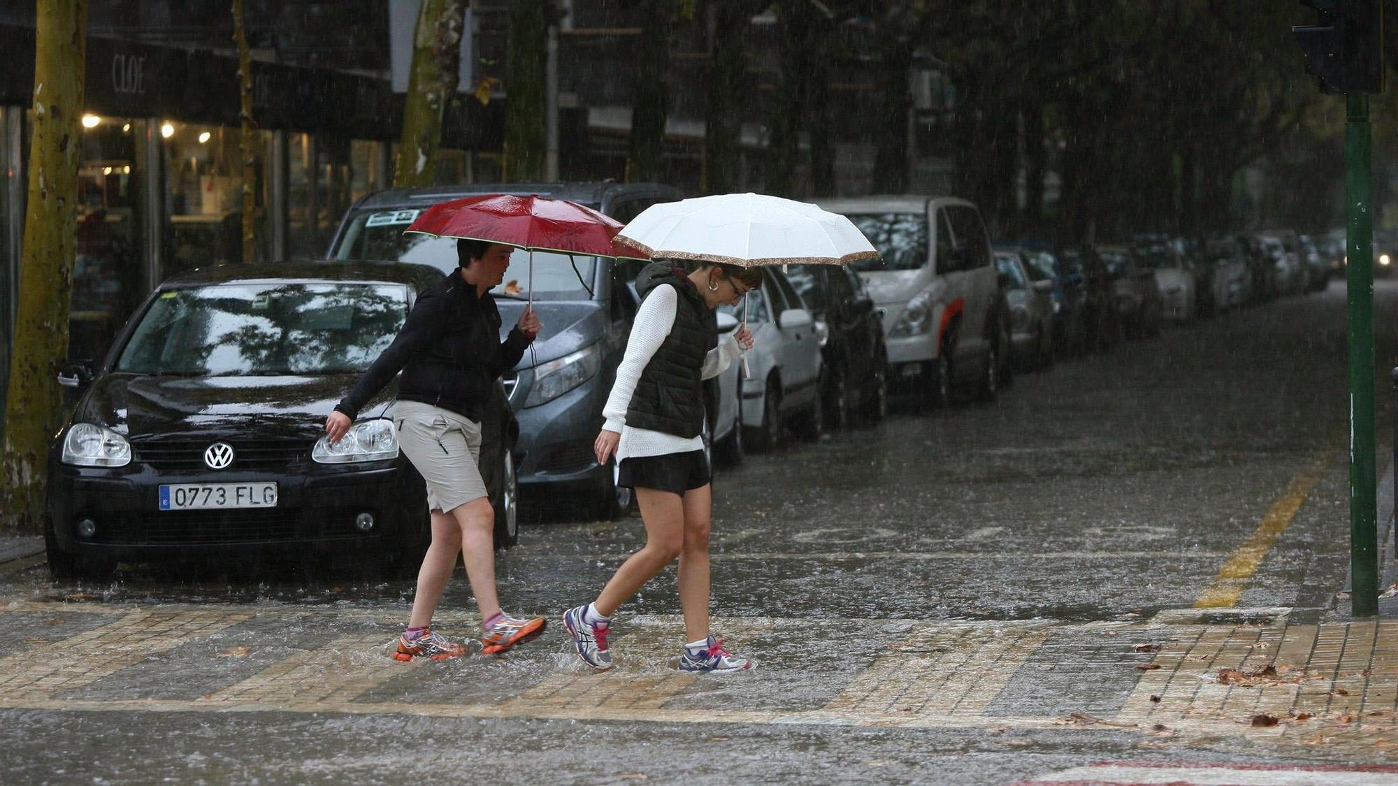 Mujeres cruzan una calle de Salou bajo la lluvia.