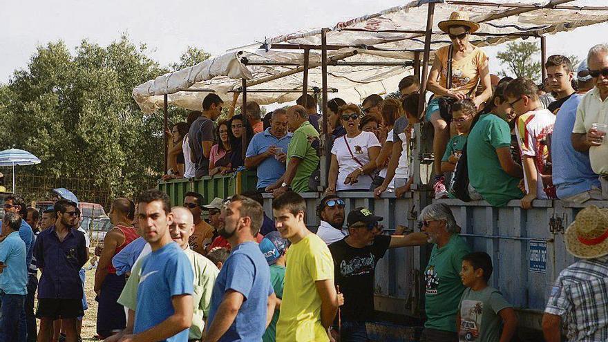 Vecinos de Fuentelapeña subidos a los remolques. A la derecha, el público cita a un toro desde las talanqueras en un encierro en las fiestas.