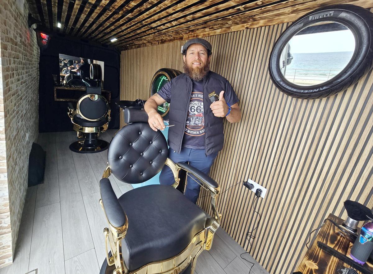 El barbero Juan Carlos Sánchez, en su peluquería móvil en Samil, la única de Galicia