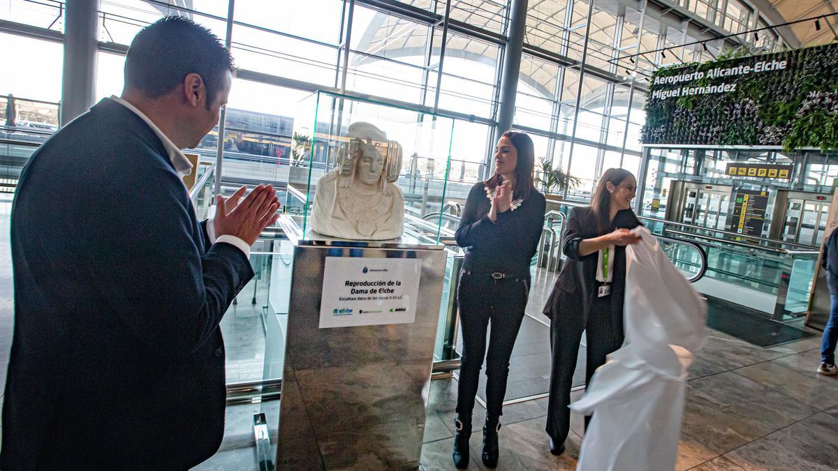 Los ediles de Turismo y Cultura, junto a la responsable del Gabinete de Dirección del aeropuerto destapan la reproducción del busto íbero en su nueva ubicación.