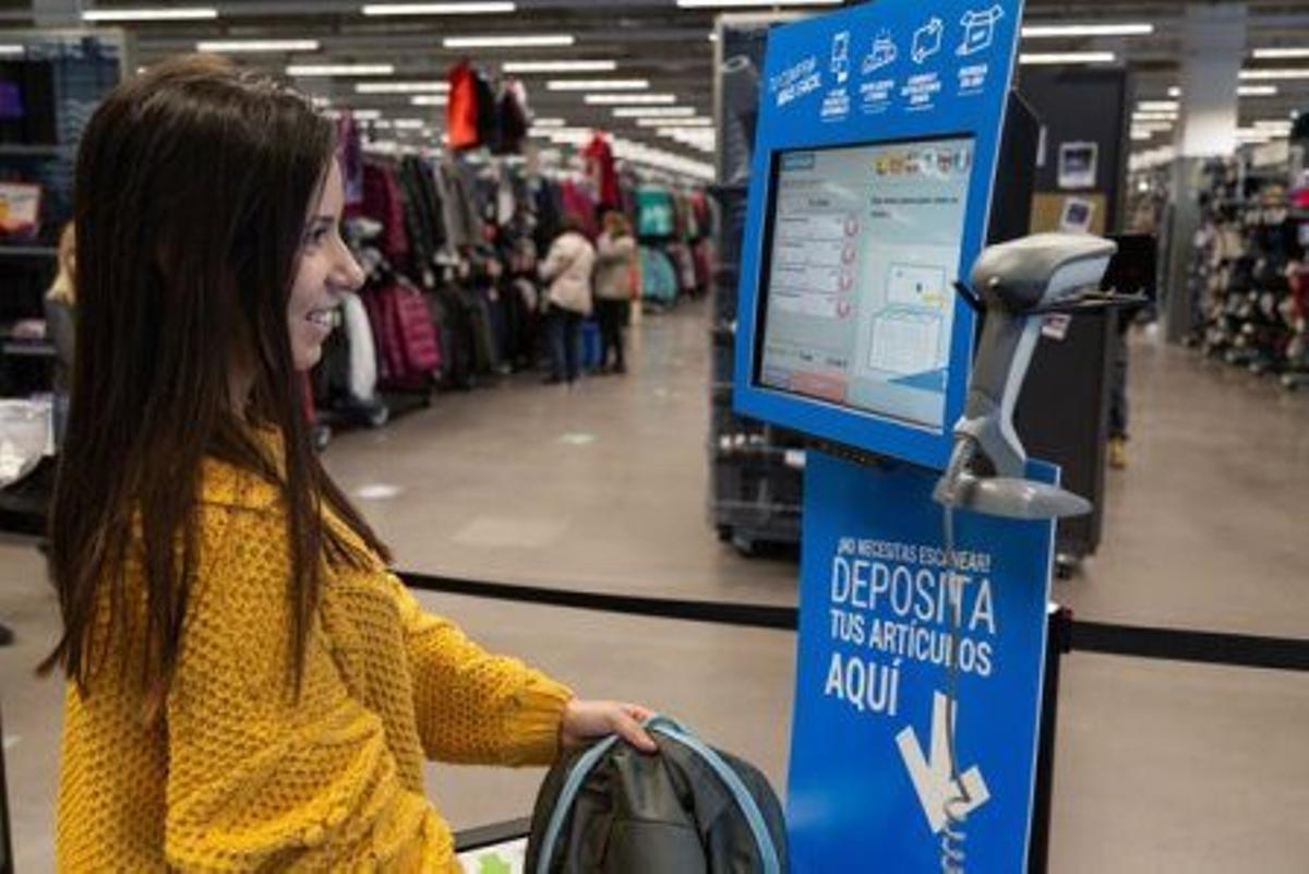 Una señora pasa por una caja autoservicio de Decathlon