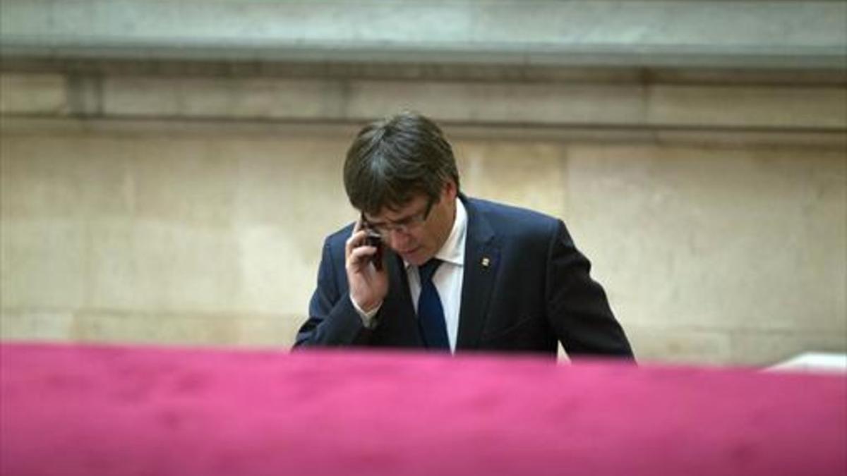 El 'president' Puigdemont habla por teléfono, ayer,a su llegada al Parlament.