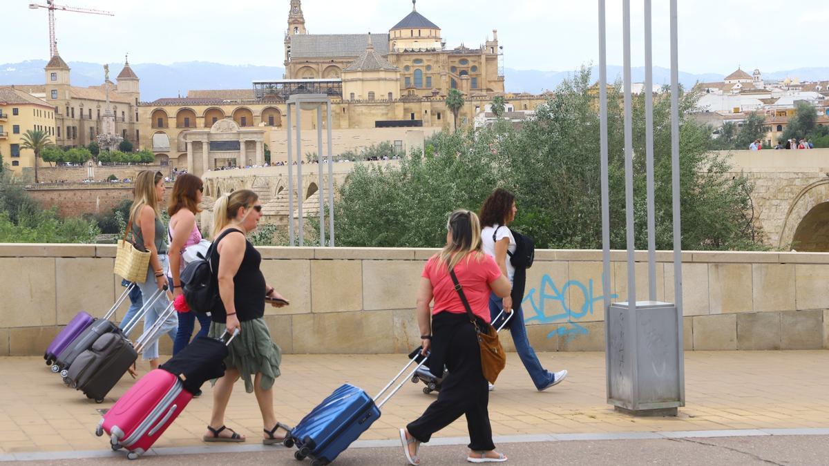 Varias mujeres pasean con maletas por la Acera Mira al Río.