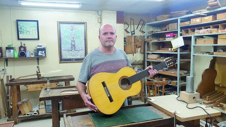 Manuel Reyes hijo muestra una de las guitarras que trabaja en el taller familiar que inició su padre.