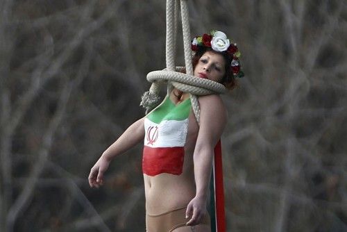 A topless activist of women's rights group FEMEN hangs from a bridge as they stage a protest against Iran's President Hassan Rouhani visit to Paris