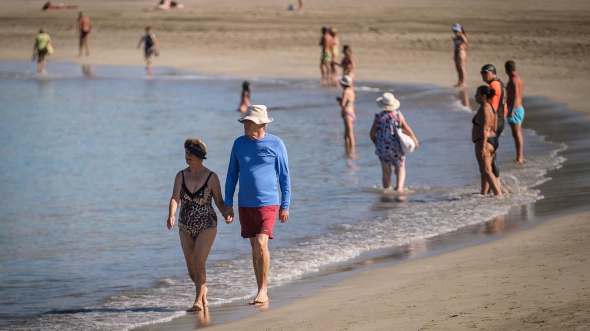 Dos turistas pasean por una playa de Tenerife.