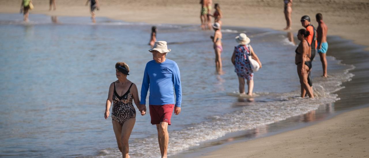 Dos turistas pasean por una playa de Tenerife.