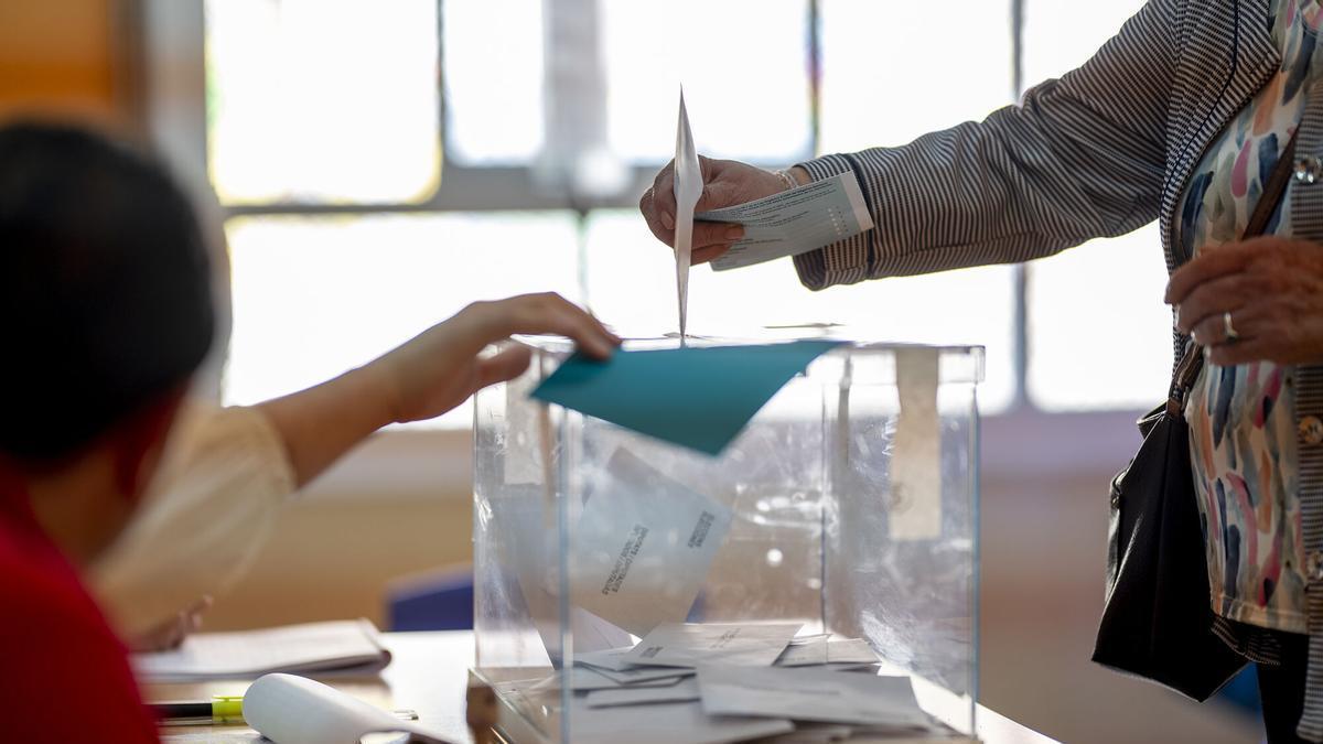Un elector deposita en la urna la papeleta con su voto durante unas elecciones.