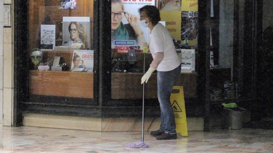 Una mujer limpia una zona comercial en La Laguna.