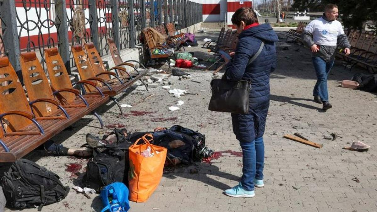 Una mujer mira su teléfono entre las víctimas que yacen en la plataforma después de un ataque con cohetes en la estación de tren en la ciudad oriental de Kramatorsk.