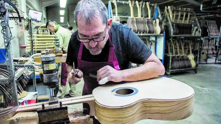 Un operario de la empresa de Muro construyendo  una guitarra con madera  de  olivo | Lucio Abad