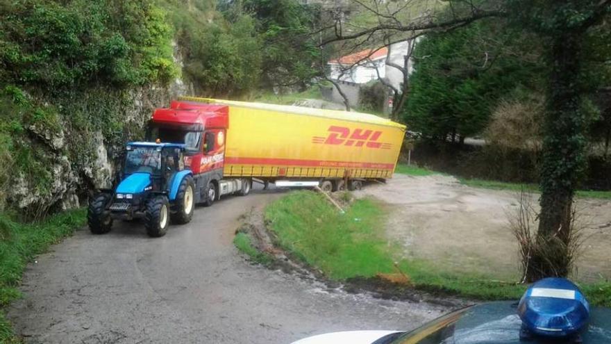 Un tractor intenta remolcar al camión atascado en Vidiago, ayer.