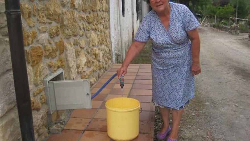 María Elda Redondo, cargando agua en un cubo, en Coya.