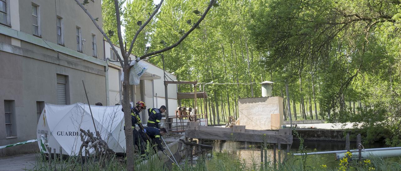 Los bomberos acercan el cadáver a la compuerta para sacarlo del agua.