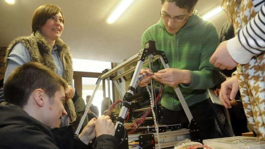 Varios alumnos del curso comprueban el funcionamiento de una de las impresoras 3D. // Noé Parga