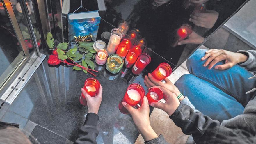 Una compañera de clase de las gemelas pone una vela en el portal donde vivían, en La Ería, ayer por la tarde, acompañada de otros amigos