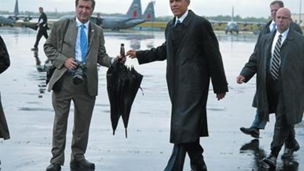 Obama da el paraguas a su fotógrafo oficial, Pete Souza en Charlotte, ayer.