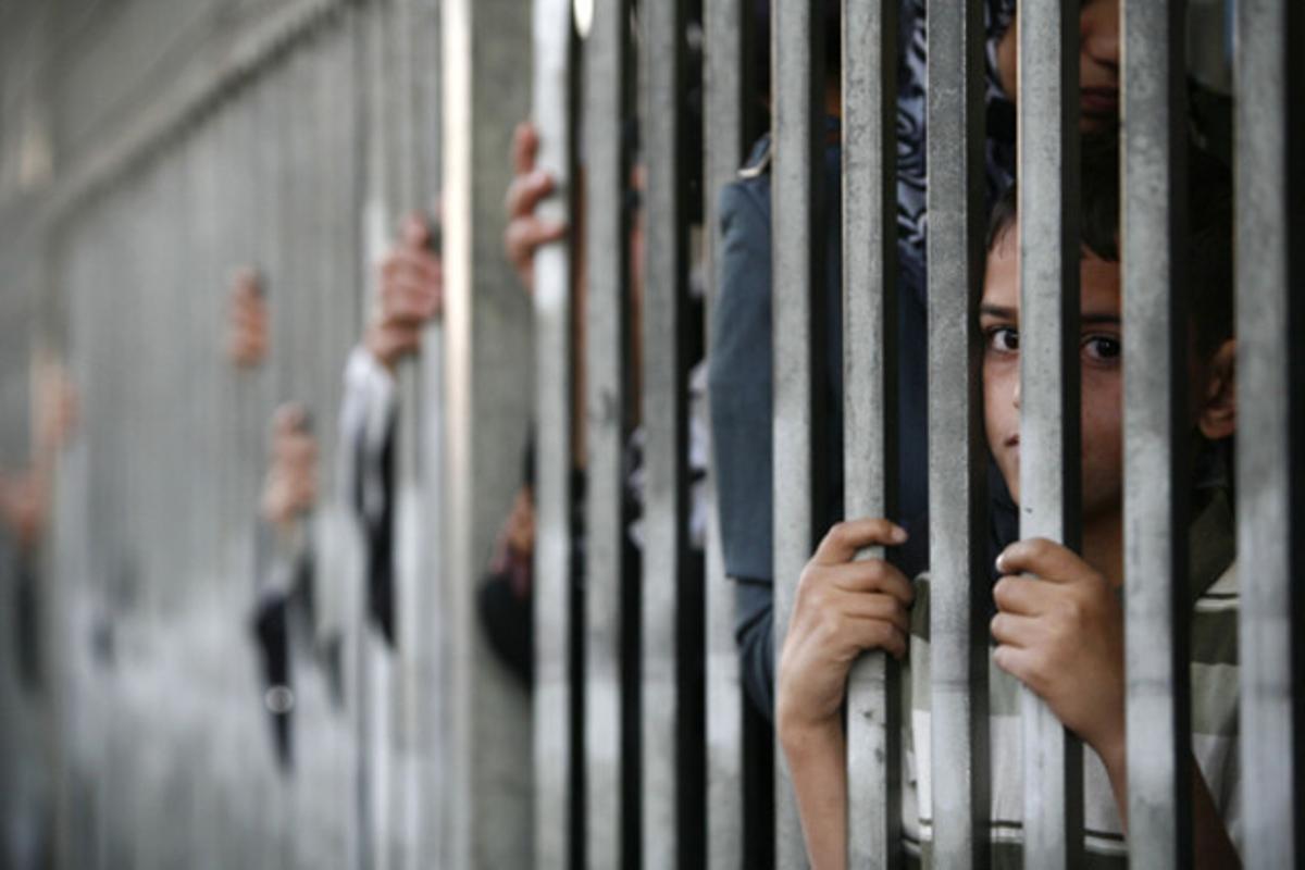 Un nen palestí observa entre els barrots mentre espera per travessar el punt de control israelià que controla el pas a Jerusalem.