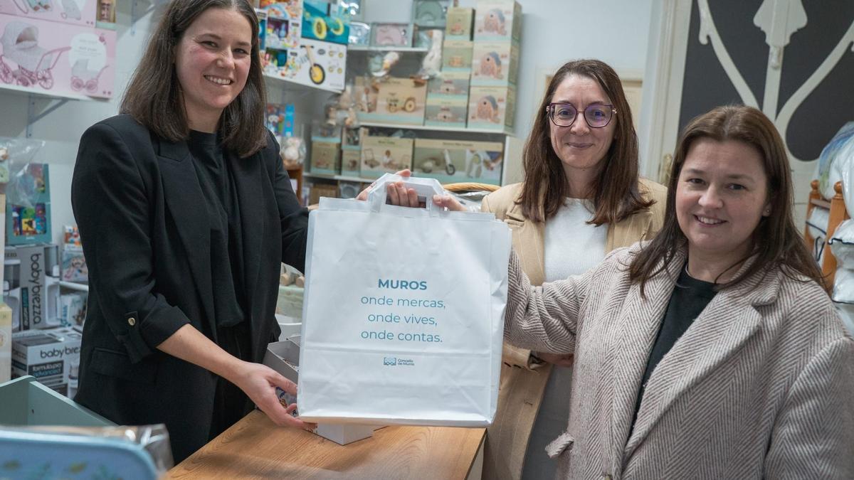 María Lago, centro, e Laura Rivadeneira, dereita, cunha comerciante de Muros.