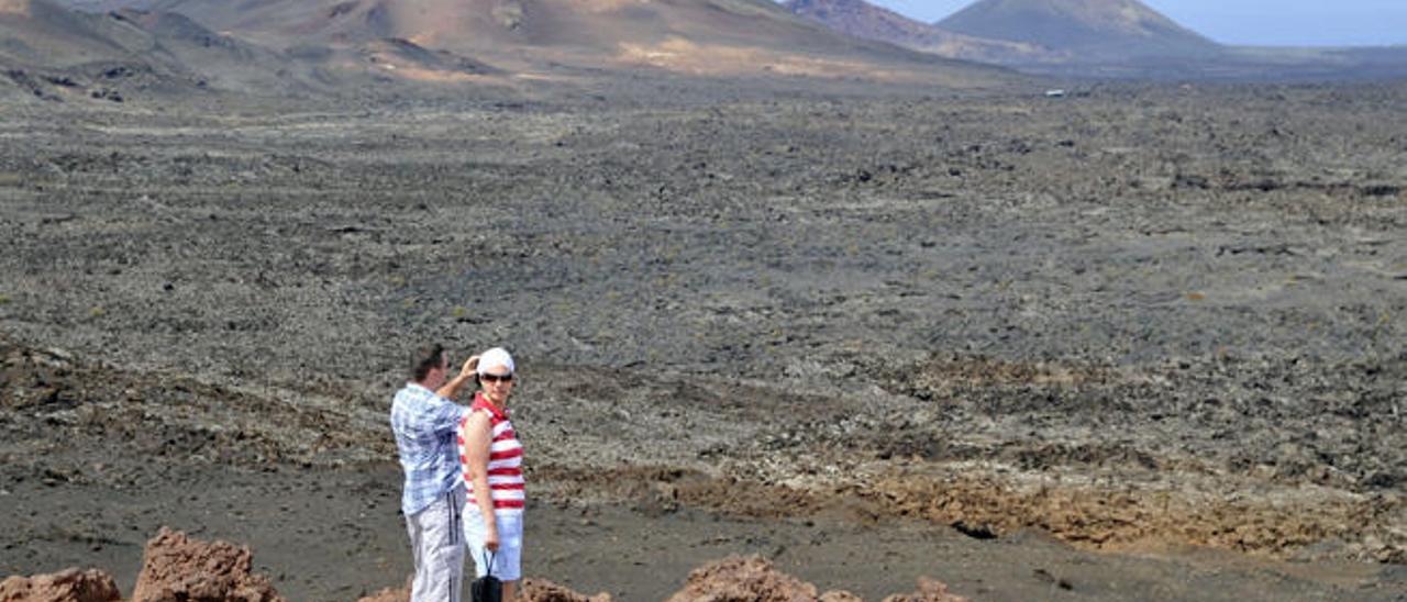 Dos turistas contemplan las coladas de Timanfaya.