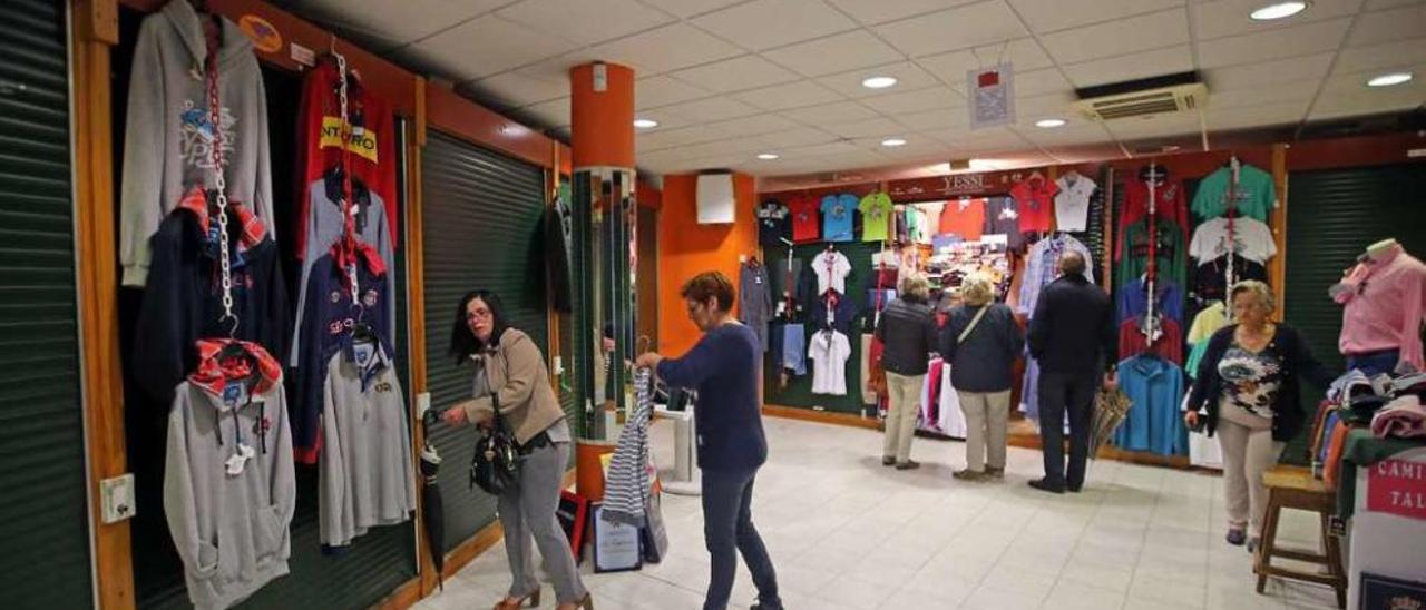 Varios clientes pasean entre los escasos puestos de venta de ropa abiertos en la planta superior de A Pedra. // Marta G. Brea