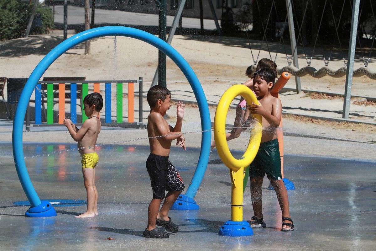 Los niños juegan con agua en un parque infantil para sobrellevar las altas temperaturas.