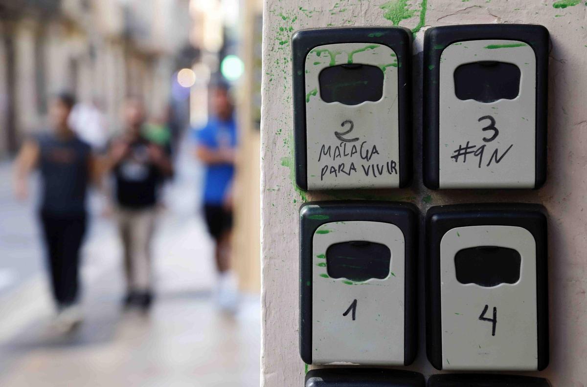 Varios turistas pasan cerca de cajetillas de llaves de los pisos turísticos que hay en el Centro de Málaga.