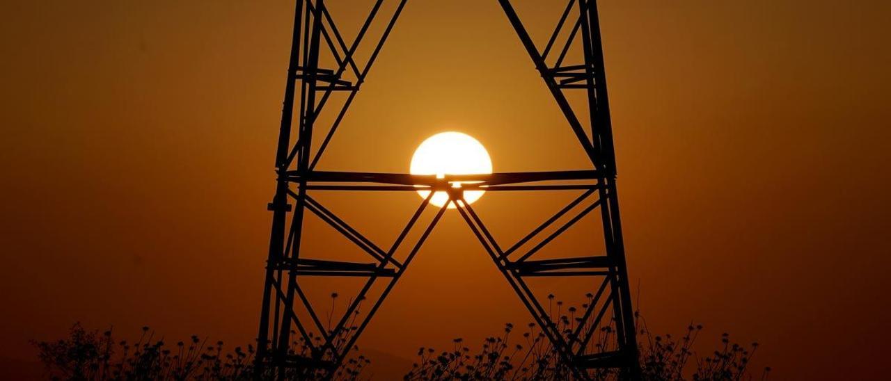 Una torre de electricidad con el sol de fondo.