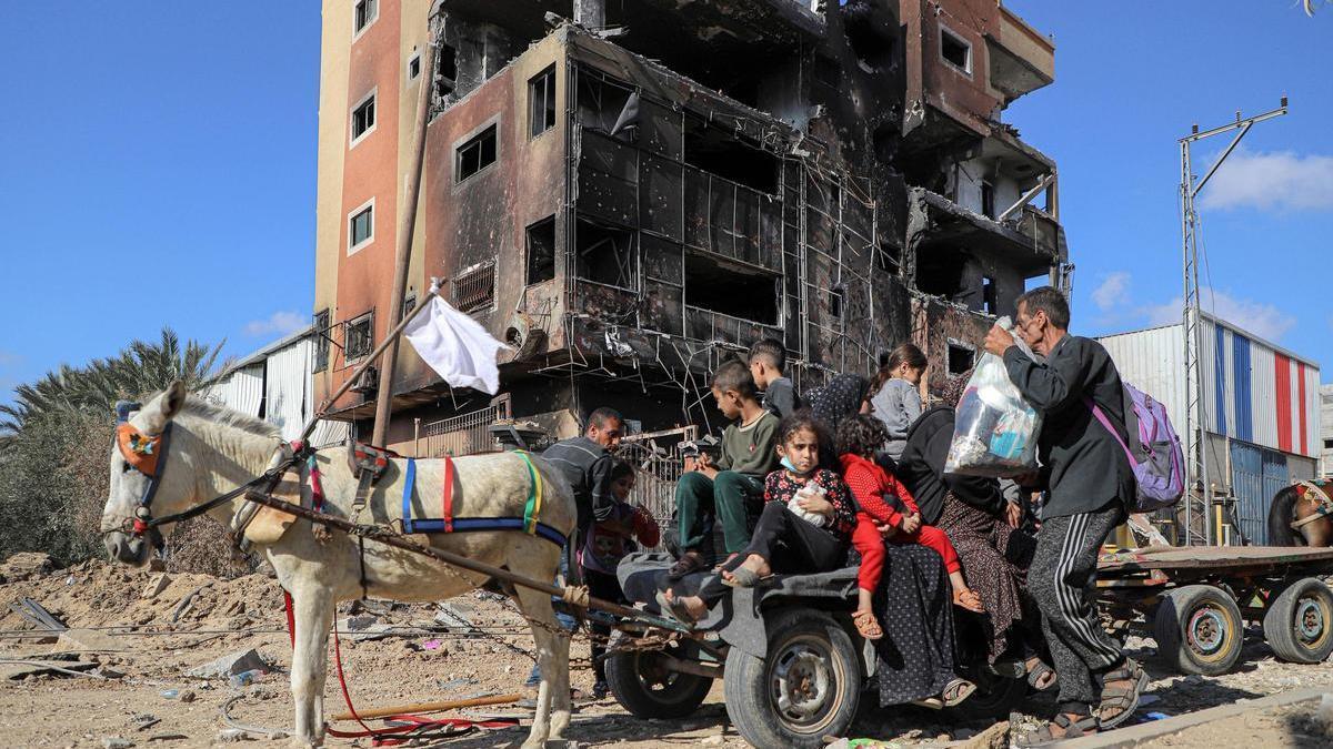 Una familia escapa del horror frente a un edificio bombardeado en la Fraja de Gaza.