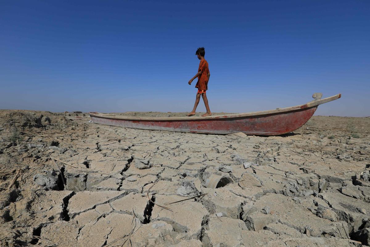 Un niño camina sobre un bote abandonado en el lecho seco de un río en Al-Chibayish, en la provincia de Dhi Qar, en Irak, el 28 de junio del 2022.