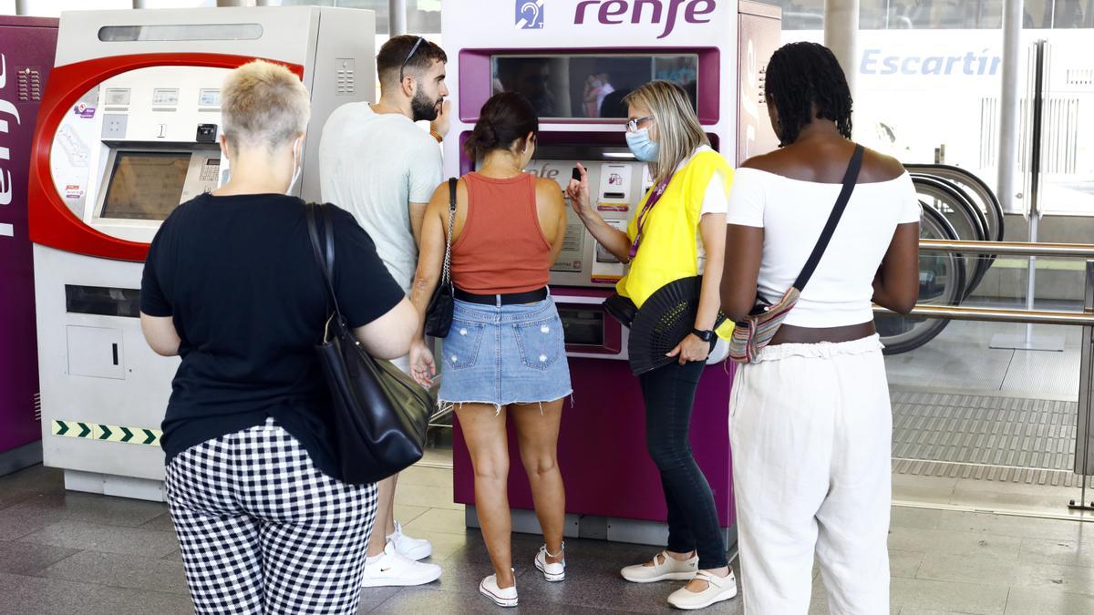 Una trabajadora de Renfe ayuda a varios usuarios a obtener su abono para viajar de forma gratuita en Cercanías y Media Distancia en la Estación de Goya de Zaragoza.