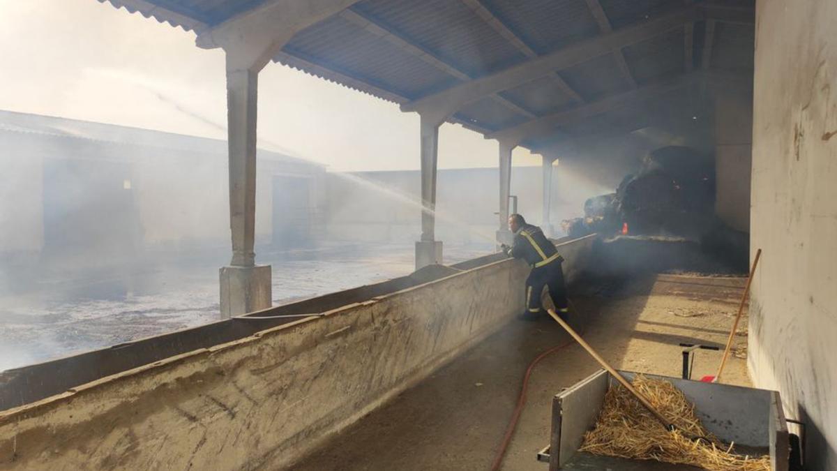 Un bombero trata de sofocar el fuego en los establos de Aszal.