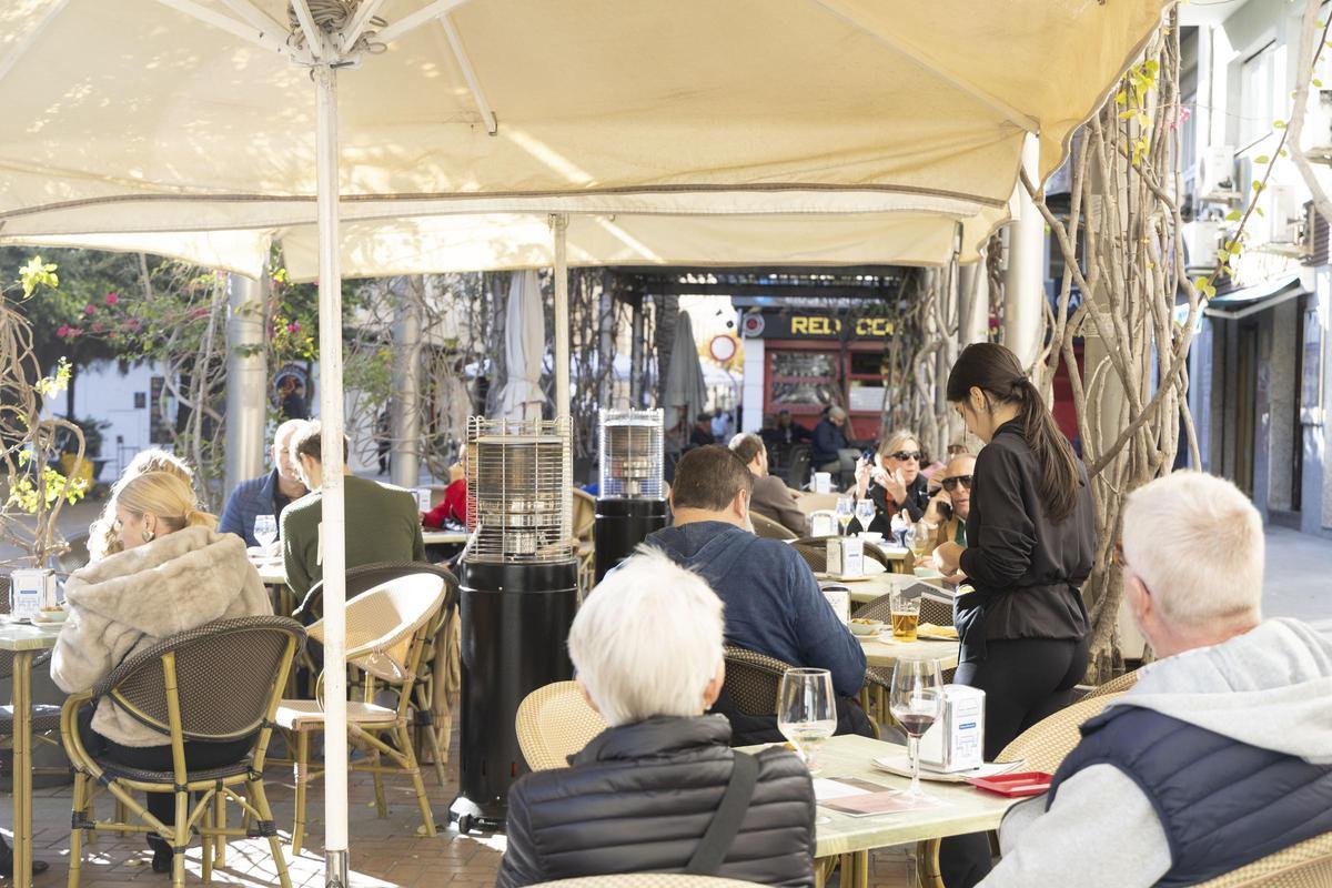 Una camarera atendiendo la terraza de un restaurante en Alicante.