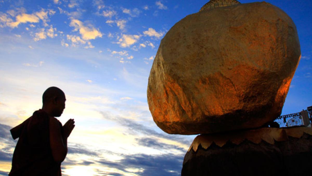 Un monjo budista resa davant una pagoda a Myanmar.