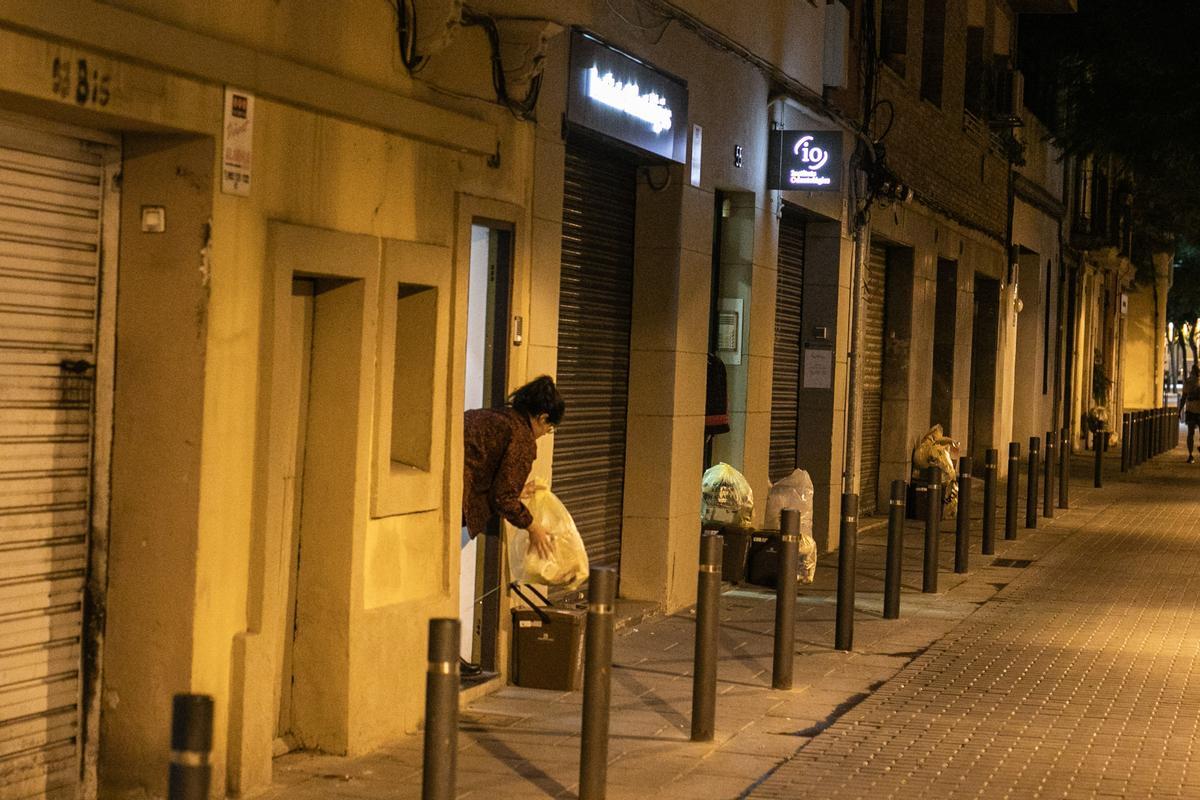 Una mujer saca la basura a la puerta de su casa, cerca de Gran de Sant Andreu.