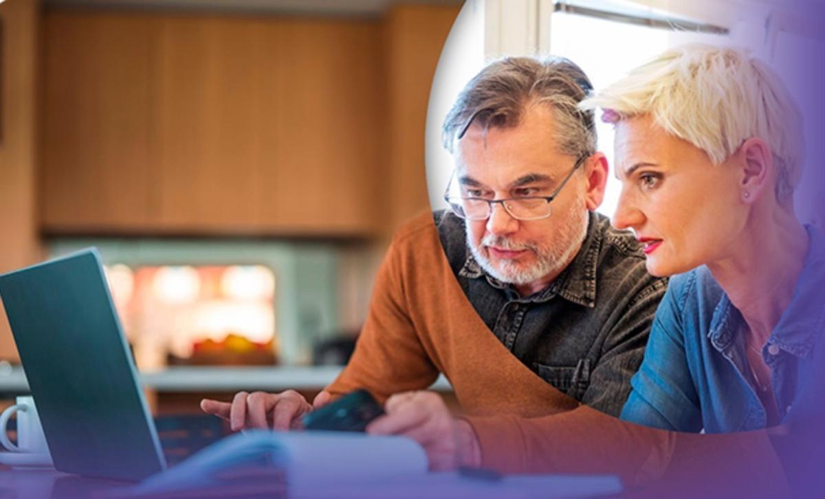 Dos personas mayores consultan el ordenador.