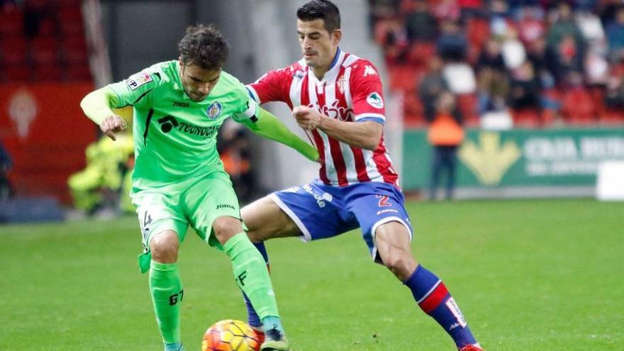 Pedro León protege el balón ante la presión de Luis Hernández en el partido de la primera vuelta en El Molinón.