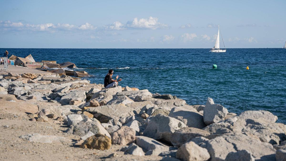 Un hombre contempla desde la playa de Bogatell, en el espigón de la Mar Bella, el espectáculo de inauguración de la Copa América de Vela.